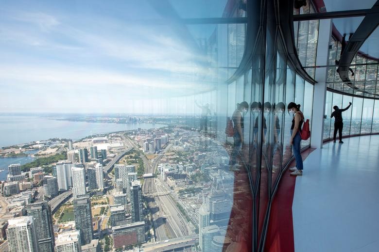 Visitors view panoramic city scenes from the 1,815 feet high CN Tower, which reopened for the first time since coronavirus restrictions were imposed in Toronto, Ontario, Canada. REUTERS/Carlos Osorio